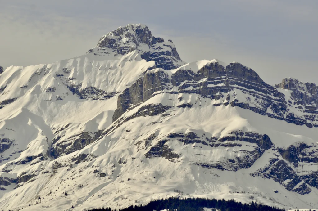 Snowy mountains & rocky cliffs of the Aravis ridge. In the foreground, the 4 humps of the quatre têtes, behind, the pointe percée, 2,752m